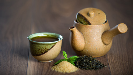 Teapot, cup of black tea with mint leaves and brown sugar