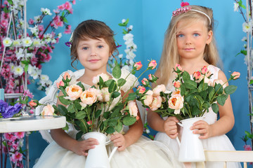 Two pretty little girls in white dresses hold roses in room