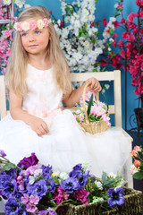Portrait of blonde little girl in white dress holds basket
