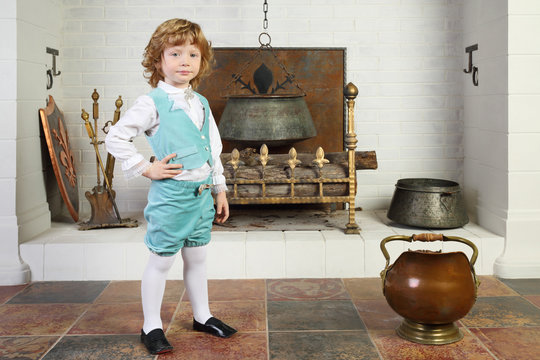 Little Boy In Medieval Costume Stands Near Fireplace