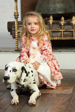 Happy pretty little girl in medieval costume sits with dalmatian