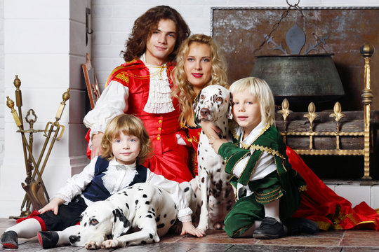 Happy father, mother and two sons in medieval costumes sit