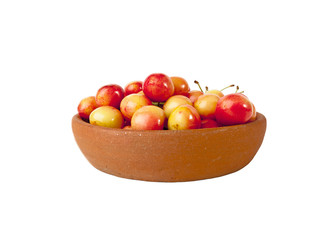 Red and yellow cherries in clay bowl on white