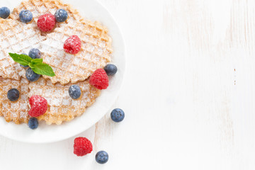 Belgian waffles with fresh berries on white wooden table