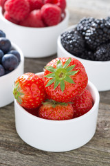 fresh strawberries in a bowl and berries, closeup, vertical