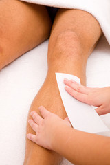 Close-up of therapist waxing man's leg