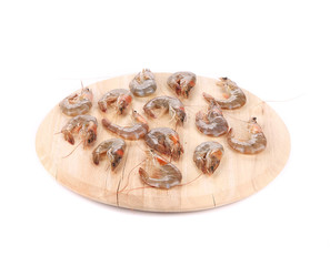 Raw shrimps on wooden platter.