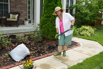 Old lady at work in the garden cleaning flowerbeds - Powered by Adobe