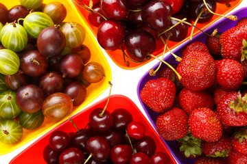 colored berries in bowls and white background