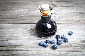 blueberry syrup in glass bottle or mixture, on wooden background