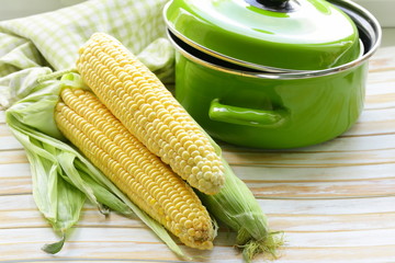 ripe yellow corn and green pan on a wooden background © Olga Kriger