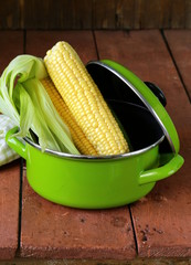 ripe yellow corn and green pan on a wooden background © Olga Kriger