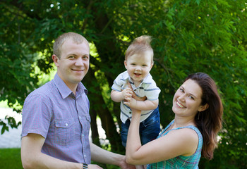 Happy family outdoors  mum and dad hold baby boy kid