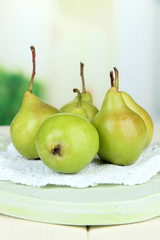 Pears on wooden cutting board, on light background