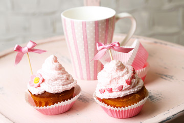 Tasty cup cakes with cream on wooden chair