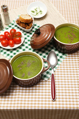 Tasty soup in saucepans on tablecloth, close up