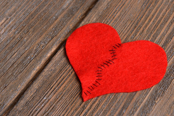 Broken heart and thread on wooden background