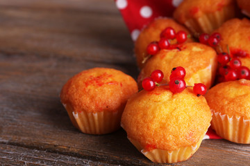 Tasty muffins with red currant on wooden background