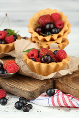Tasty tartlets with berries on wooden table