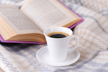 Cup of coffee on plaid with book