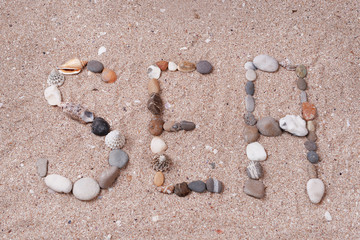 Word sea made from sea shells and stones on sand