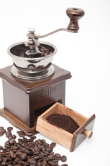 Isolated vintage coffee bean grinder and fresh ground coffee