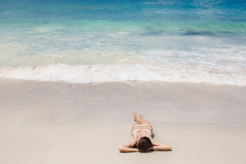 Fototapeta na wymiar Young woman lying on tropical beach