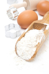 scoop with wheat flour, eggs and cookie cutters isolated