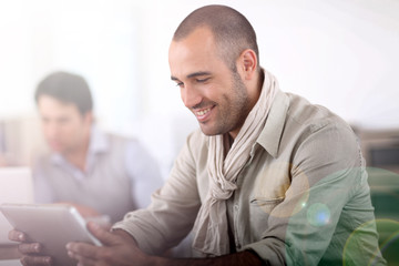 Smiling man in office using digital tablet
