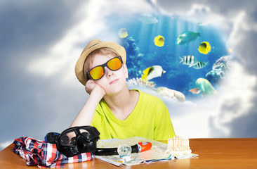 Boy sitting at the table and dreaming of snorkeling vacations