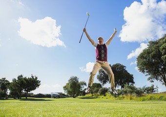 Excited golfer jumping up holding club