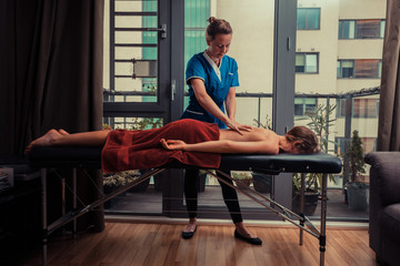 Massage therapist treating patient at home - obrazy, fototapety, plakaty