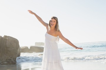 Fototapeta na wymiar Beautiful blonde in white sundress on the beach