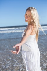 Fototapeta na wymiar Woman in white dress offering her hand on the beach