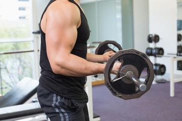 Fototapeta na wymiar Muscular bodybuilder lifting heavy black barbell weight