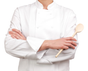 Photograph of a bust Cooker arms crossed holding a wooden spoon