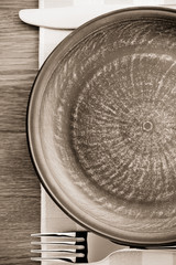 plate, knife and fork at napkin on wood