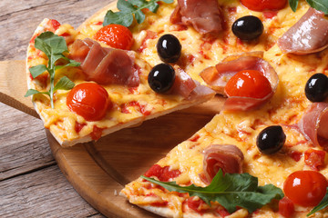 piece of pizza with ham, tomatoes, black olives and arugula