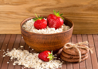 Oatmeal with strawberries in the bowl and cookies