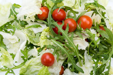 Heap of ruccola, lettuce leaves and cherry tomatoes