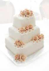 Wedding cake with pink flowers on light background