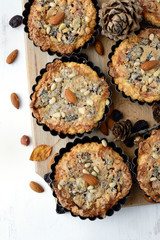 Tarts with nuts and raisins filling on a wooden board.