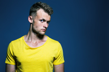 Emotive portrait of muscular young handsome man in bright yellow