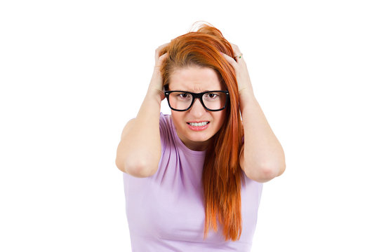 Stressed young woman pullling her hair out, white background 