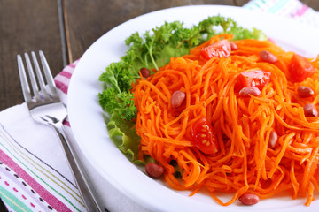 Carrot salad on plate on napkin on wooden table