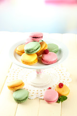 Gentle macaroons in vase on table on light background