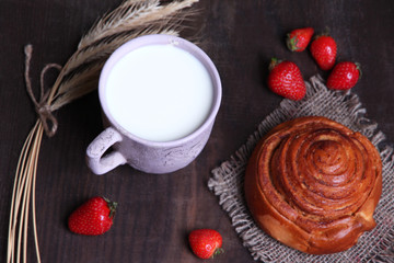 Ripe sweet strawberries in wooden bowl and mug with milk