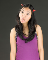 Devil side of a young Asian woman sticking out her tongue