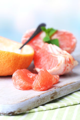 Ripe grapefruits on cutting board, on wooden background