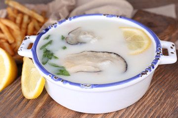 Tasty soup with oysters on wooden table